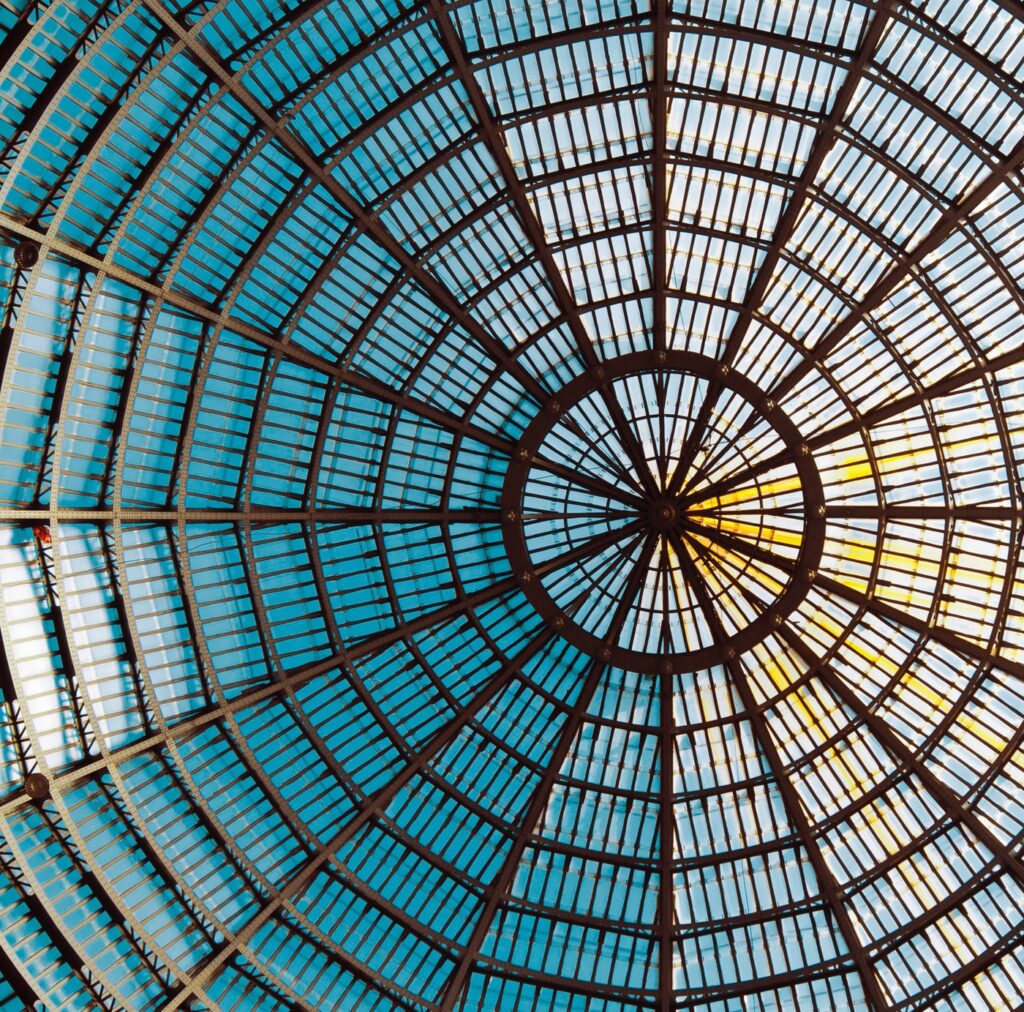 Architectural image of a glass ceiling with repetitive circular shapes and a single focal point in the middle.