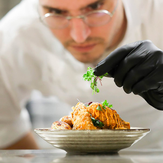 Everyday Kitchen Brand Positioning — close up image of chef garnishing food dish with intense concentration. 