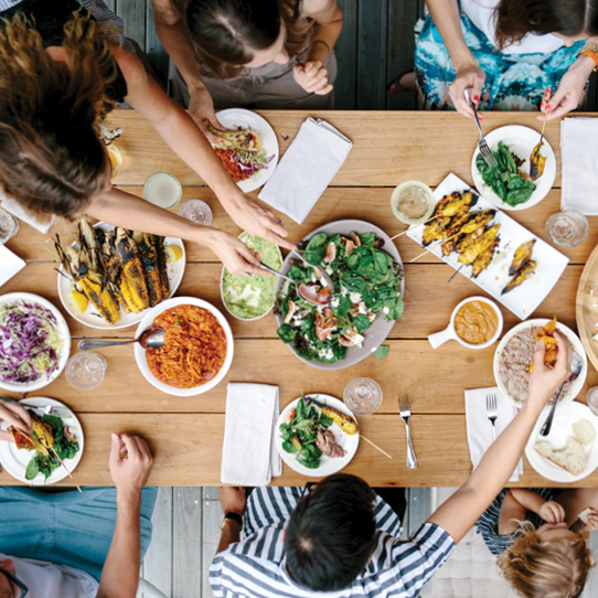 Everyday Kitchen Brand Positioning — a group of people sitting around a table reaching for multiple different food dishes. 